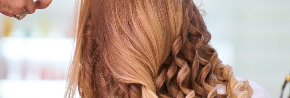 Close-up of a stylist curling blonde hair into glamorous curls at a salon.